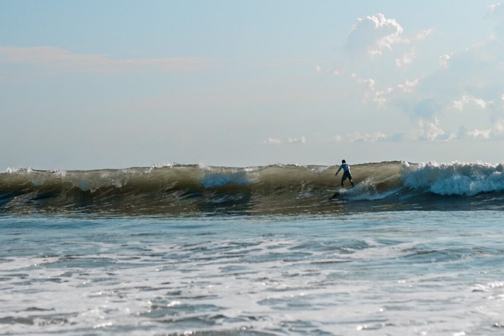 Surfer riding a large wave on a clear day, showcasing the sport's thrill and connection with nature. Ideal for surf culture content.
