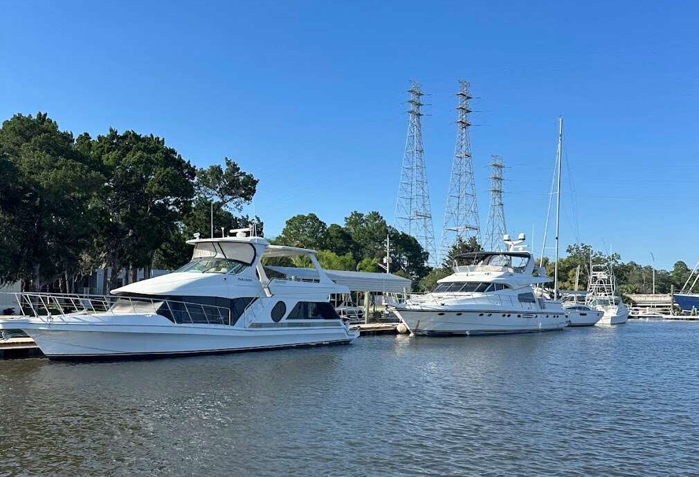 Luxury yachts docked in a marina, with clear blue skies and power lines in the background. The image highlights recreational boating opportunities.