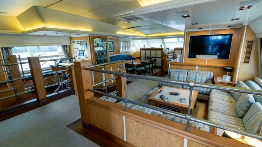 Luxurious yacht interior featuring a spacious lounge with plush seating, a dining area, and large windows for natural light.